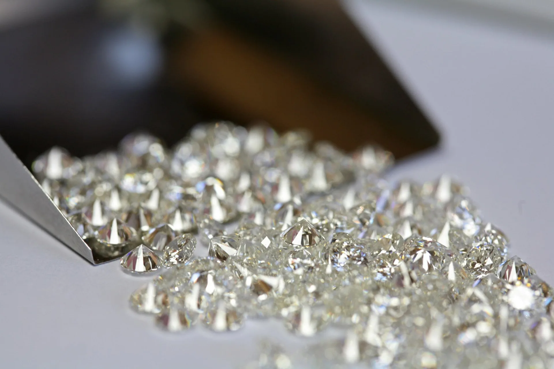 A polished parcel of loose diamonds beside a jeweller's scoop.
