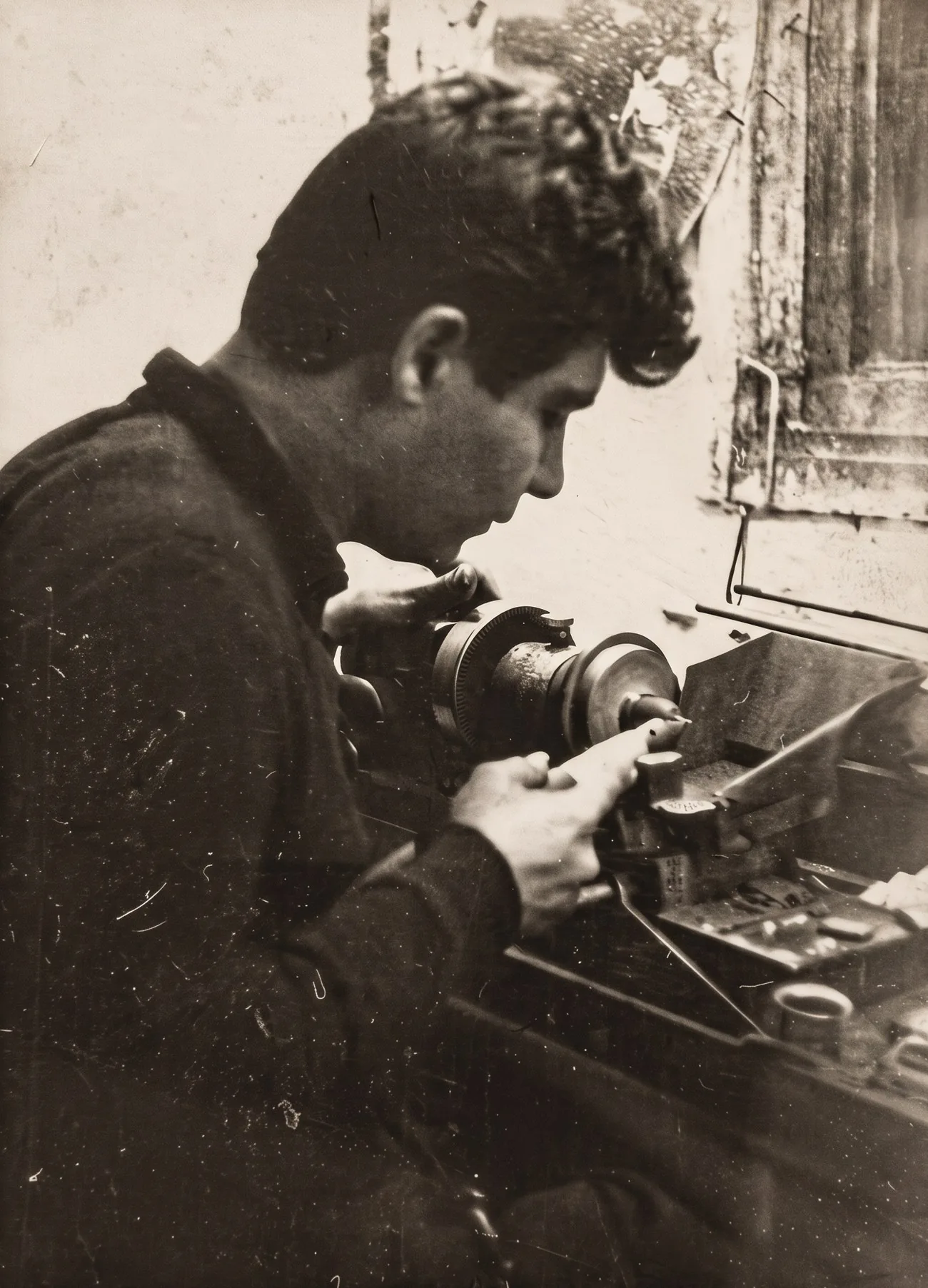 Archival black-and-white close-up of Haviv Moreno working at the cutting machine at his workshop bench, 1960s.