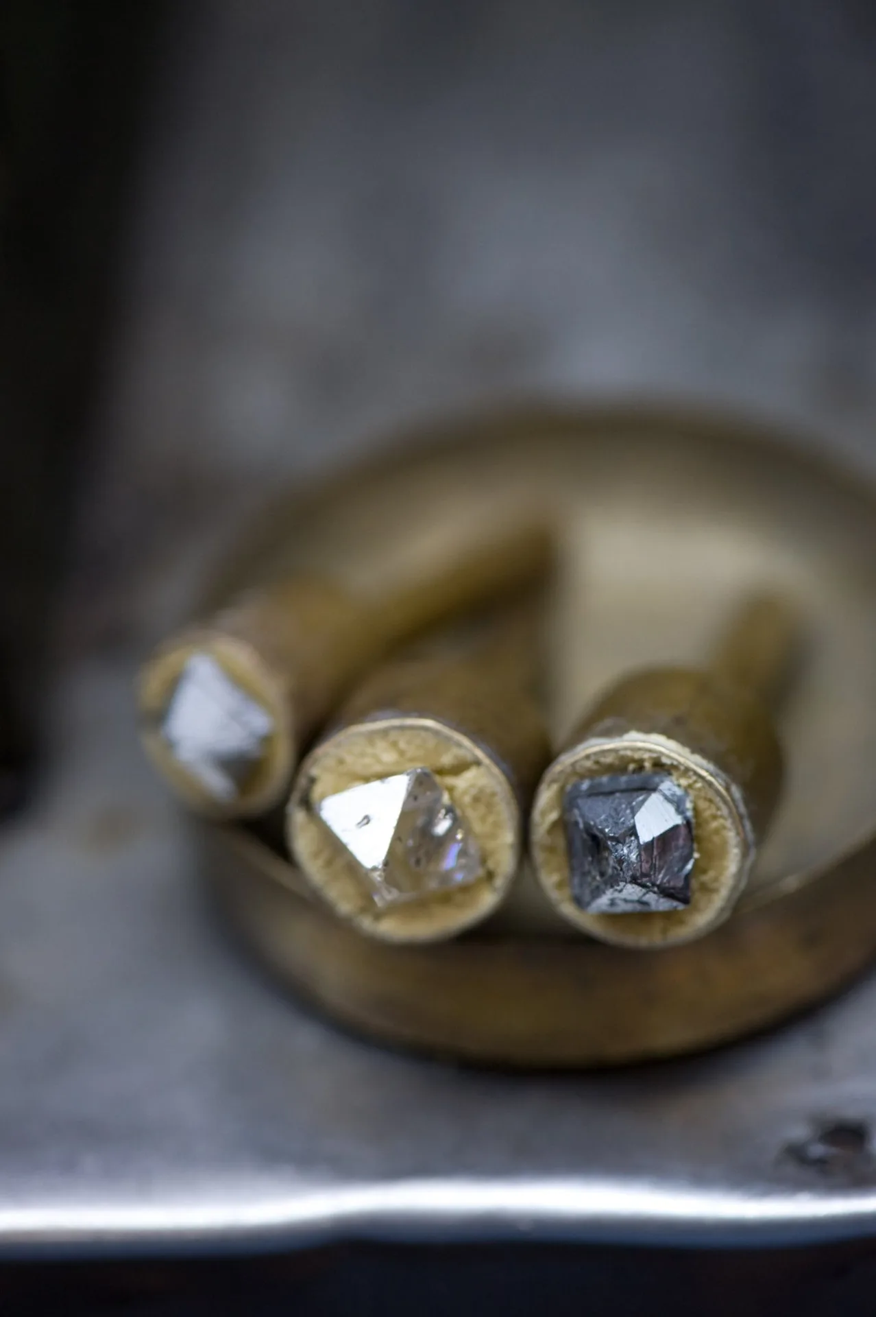 Three rough diamonds mounted on brass dops in the cutting workshop.