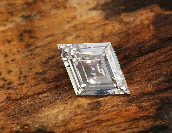 A bespoke step-cut lozenge diamond displayed on a jeweller's workbench.